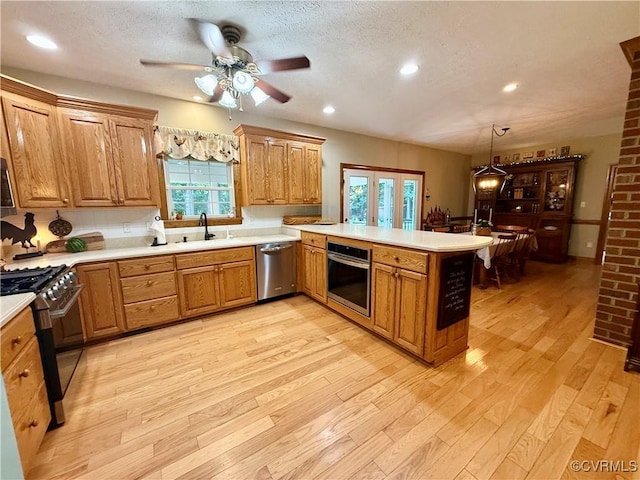 2222 Green Level Rd, King William, VA 23086 - kitchen featuring stainless steel appliances, a peninsula, brown cabinetry, a ceiling fan, and light wood-style floors
