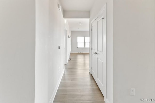corridor featuring light wood finished floors and baseboards