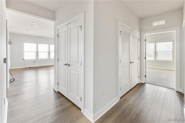 corridor with wood finished floors, visible vents, and baseboards