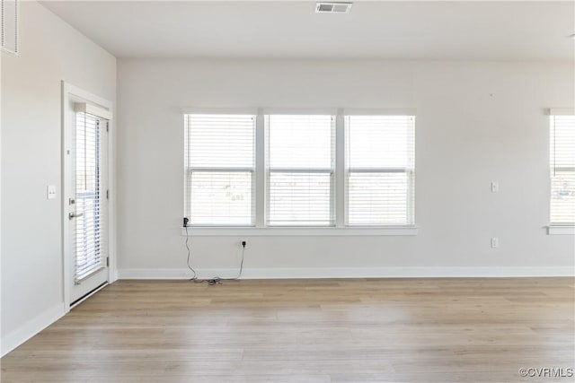 empty room featuring visible vents, light wood-style flooring, and baseboards