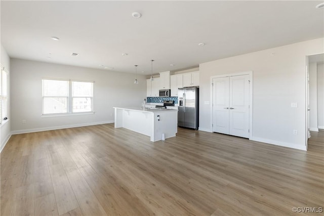 kitchen with open floor plan, baseboards, appliances with stainless steel finishes, and white cabinetry