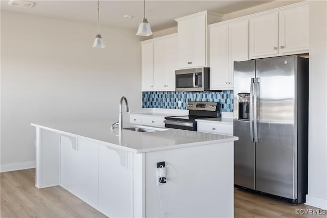 kitchen featuring stainless steel appliances, a kitchen island with sink, light wood-style floors, white cabinetry, and light countertops