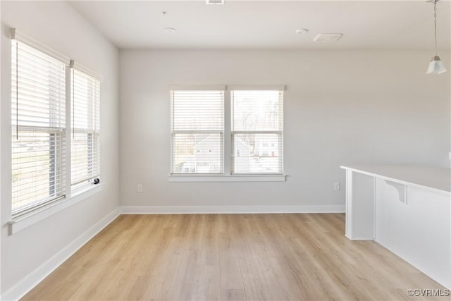unfurnished room featuring light wood-type flooring, baseboards, and a healthy amount of sunlight