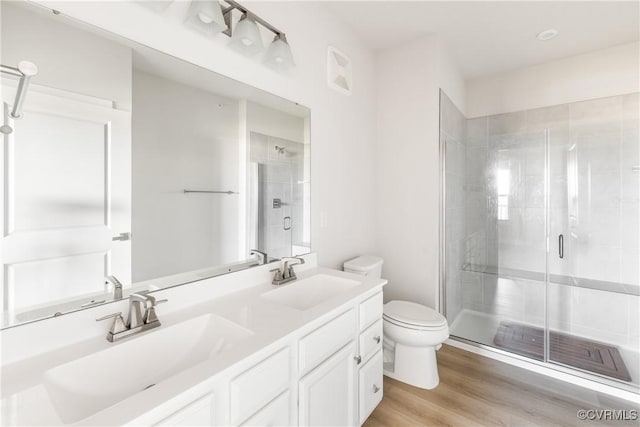 full bathroom featuring a shower stall, toilet, wood finished floors, and a sink