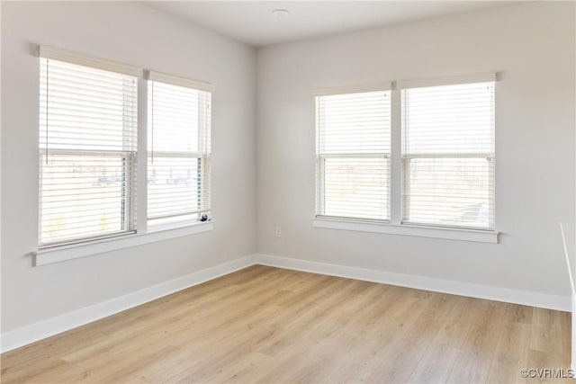 spare room featuring baseboards and light wood finished floors