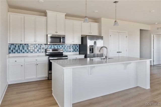 kitchen with light wood-style floors, appliances with stainless steel finishes, a center island with sink, and a sink