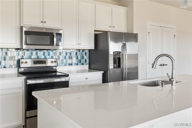 kitchen featuring white cabinets, stainless steel appliances, a sink, backsplash, and light countertops