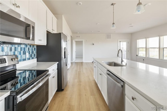 kitchen with light wood finished floors, visible vents, a sink, appliances with stainless steel finishes, and white cabinetry