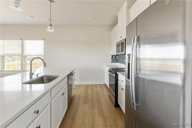 kitchen featuring a sink, stainless steel appliances, light wood finished floors, light countertops, and white cabinets