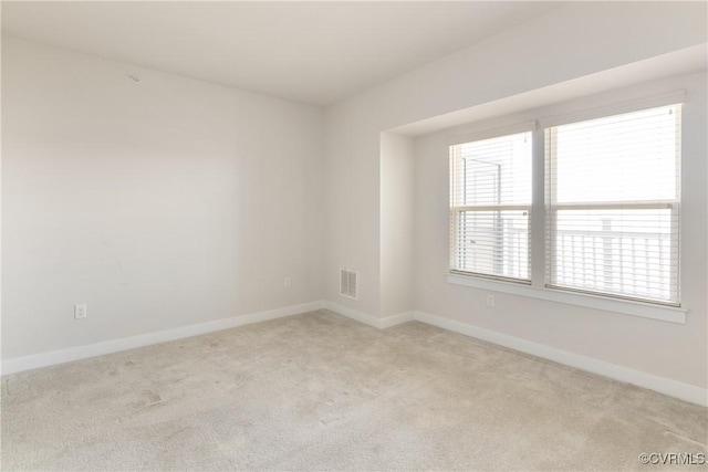 empty room with visible vents, baseboards, and light carpet