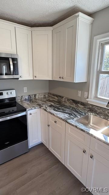 4409 Samara Dr, Henrico, VA 23231 - kitchen featuring dark wood-style floors, white cabinetry, a textured ceiling, stainless steel appliances, and a sink