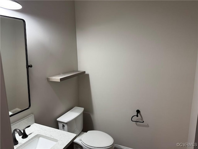 bathroom with toilet, vanity, and baseboards