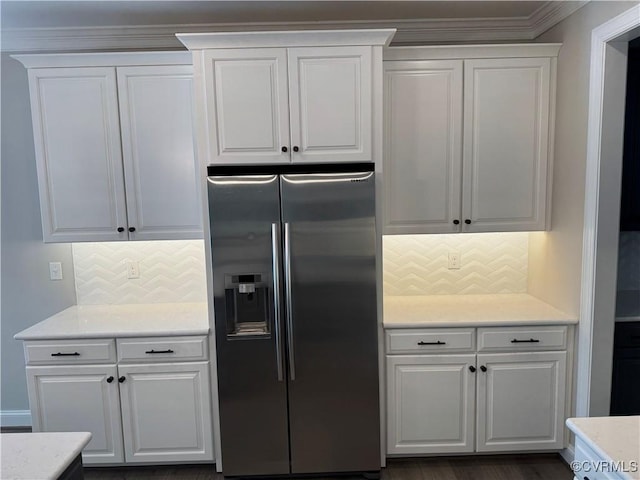 kitchen with white cabinetry, decorative backsplash, light stone counters, and stainless steel fridge