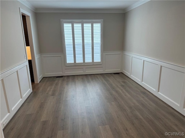 unfurnished room featuring a decorative wall, ornamental molding, a wainscoted wall, and dark wood finished floors