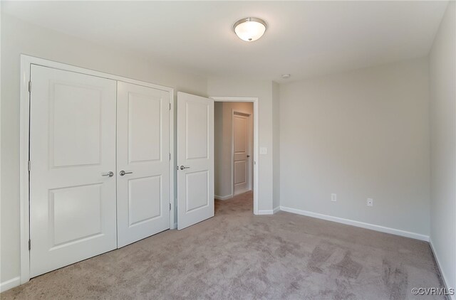 unfurnished bedroom featuring baseboards, carpet, and a closet
