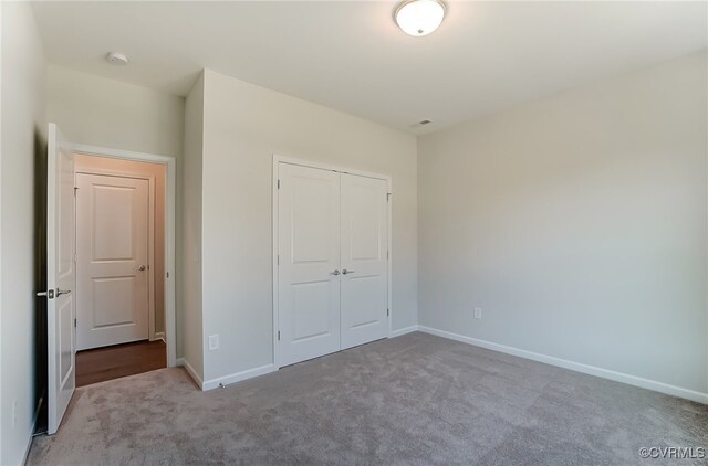 unfurnished bedroom featuring carpet floors, baseboards, and a closet