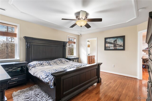 bedroom with a raised ceiling, multiple windows, and baseboards