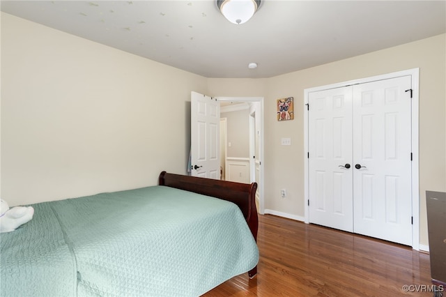 bedroom with wood finished floors, a closet, and baseboards