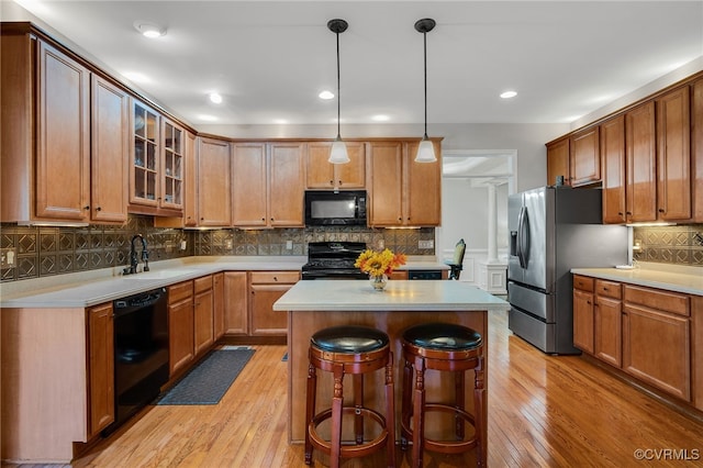 2228 Millcrest Ter, Midlothian, VA 23112 - kitchen with black appliances, decorative backsplash, light wood-type flooring, a center island, and light countertops