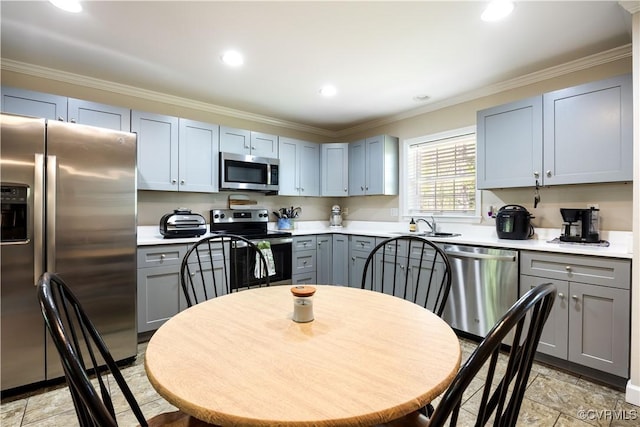 kitchen featuring light countertops, gray cabinetry, appliances with stainless steel finishes, and crown molding