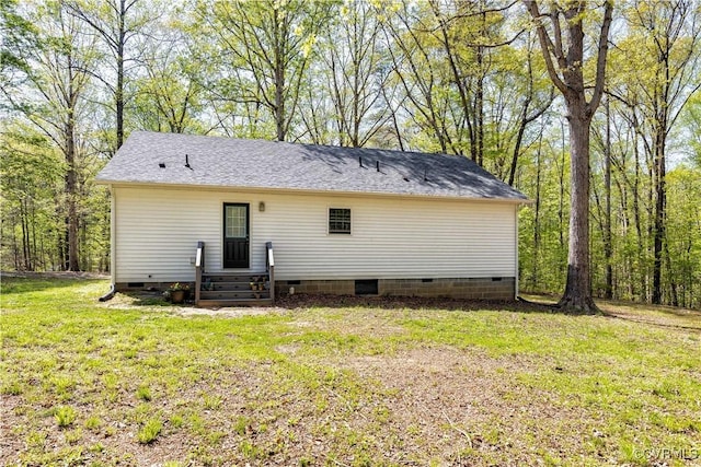 rear view of property featuring crawl space, a shingled roof, and a yard