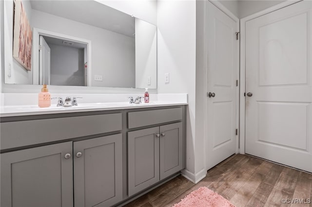 full bathroom featuring double vanity, wood finished floors, and a sink