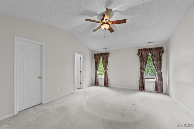 carpeted spare room featuring visible vents, vaulted ceiling, a ceiling fan, and a textured ceiling
