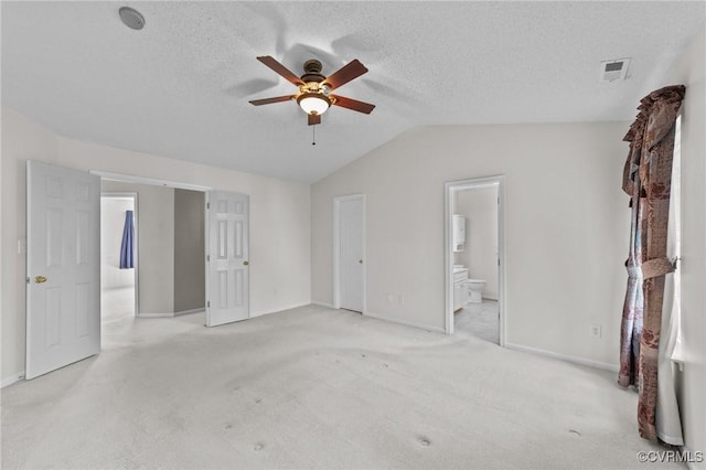 unfurnished bedroom with light colored carpet, visible vents, a textured ceiling, and vaulted ceiling