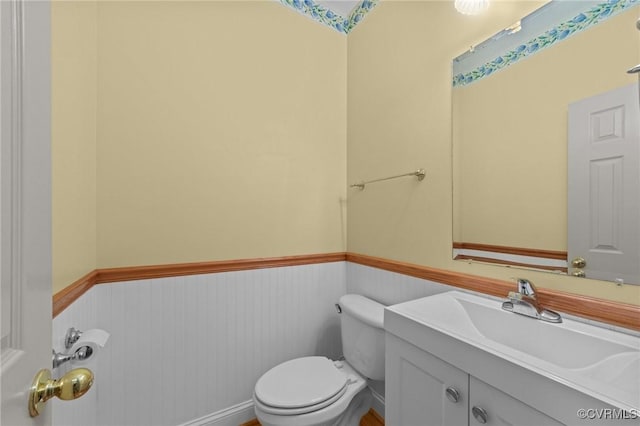 bathroom featuring vanity, wainscoting, and toilet