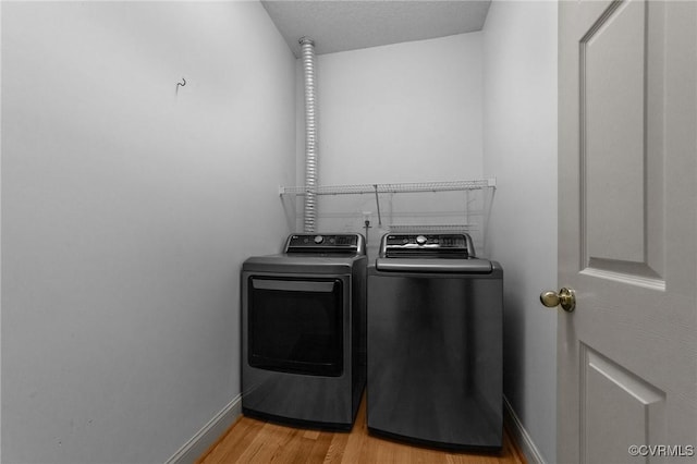 washroom with light wood-style flooring, washing machine and clothes dryer, laundry area, and baseboards