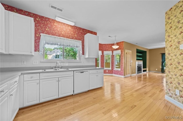 kitchen with a sink, visible vents, white dishwasher, and wallpapered walls