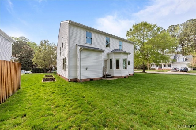 rear view of property with crawl space, entry steps, and a lawn