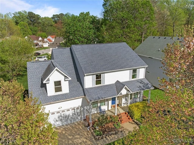 view of front facade featuring a garage, driveway, a shingled roof, and covered porch