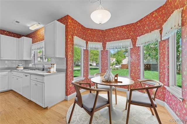 kitchen with white dishwasher, light wood-style floors, baseboards, and wallpapered walls