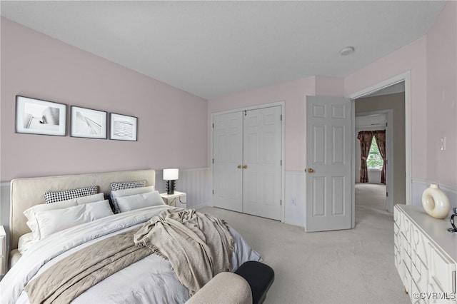 bedroom featuring light carpet, a closet, and wainscoting