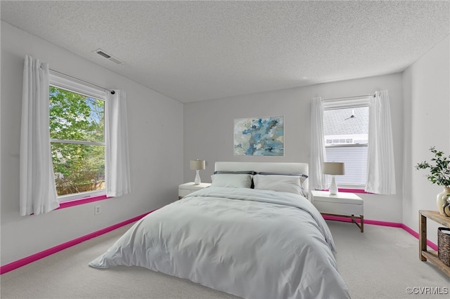 carpeted bedroom featuring visible vents, a textured ceiling, and baseboards
