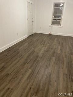 empty room featuring baseboards and dark wood-style flooring