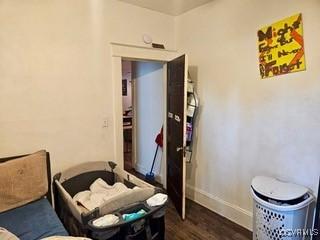 bedroom with baseboards and dark wood-type flooring