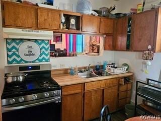 kitchen with brown cabinetry, light countertops, a sink, stainless steel range with gas cooktop, and under cabinet range hood