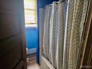 bathroom with shower / bath combo with shower curtain and wood finished floors