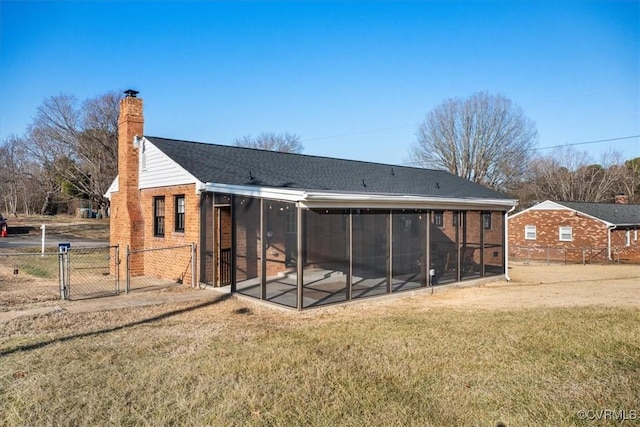 back of property with a yard, fence, a gate, and a sunroom