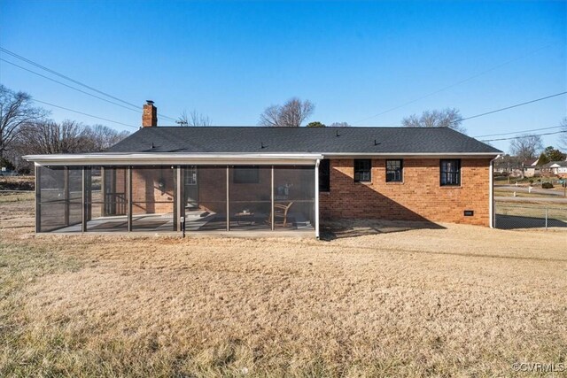 rear view of house with brick siding, fence, a chimney, and a sunroom