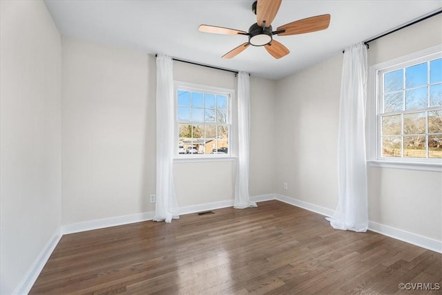 spare room featuring visible vents, a ceiling fan, baseboards, and wood finished floors