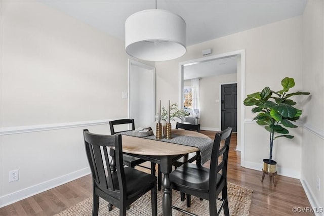 dining space with baseboards and wood finished floors