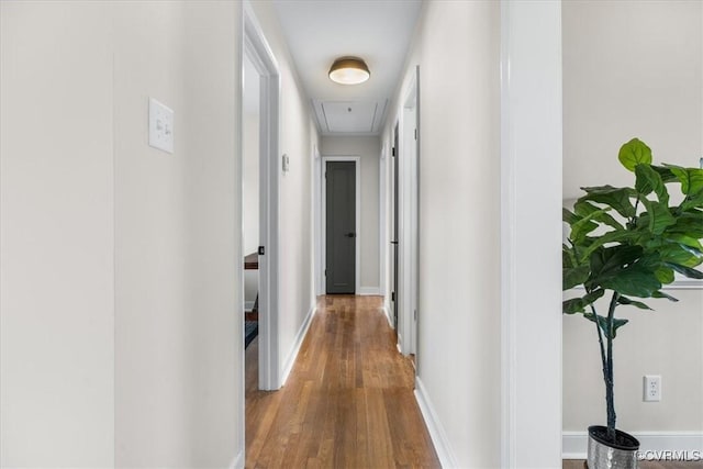 hallway with baseboards, attic access, and hardwood / wood-style flooring
