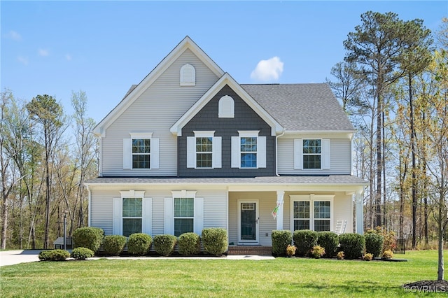 view of front of house with a shingled roof, a front lawn, and covered porch