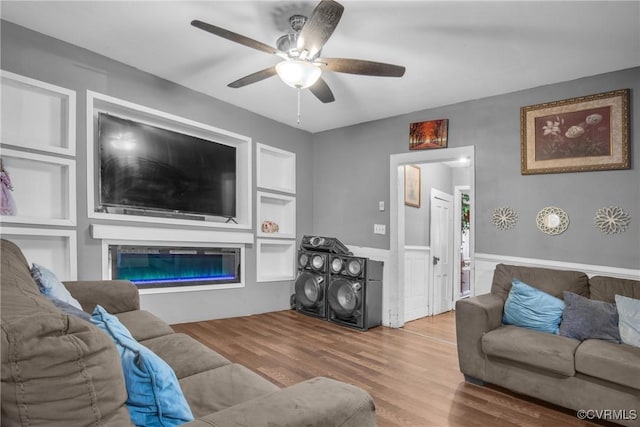 32390 S Main St, Boykins, VA 23827 - living room featuring a glass covered fireplace, wood finished floors, a wainscoted wall, and ceiling fan