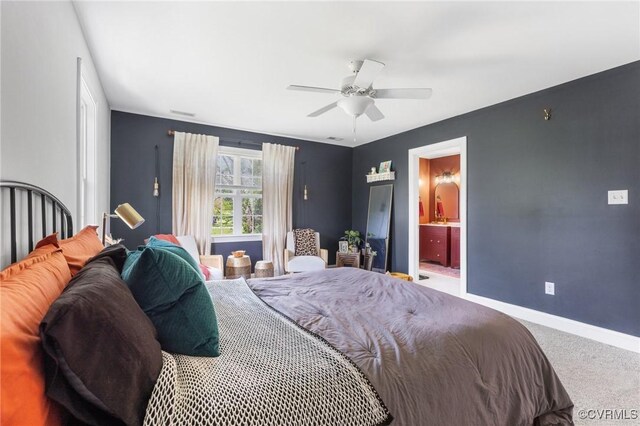 carpeted bedroom with ensuite bath, ceiling fan, and baseboards