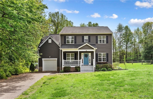 view of front of home featuring fence, driveway, covered porch, and a front yard