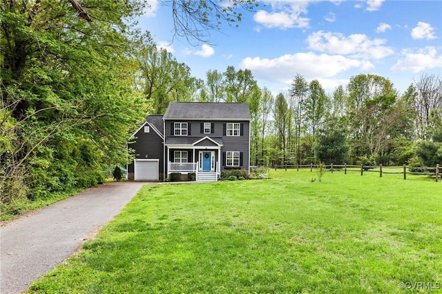 colonial-style house featuring aphalt driveway, fence, a front lawn, an attached garage, and a porch